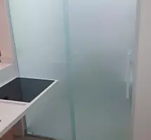 Fechamento de vidro jateado entre ambiente de cozinha e lavanderia